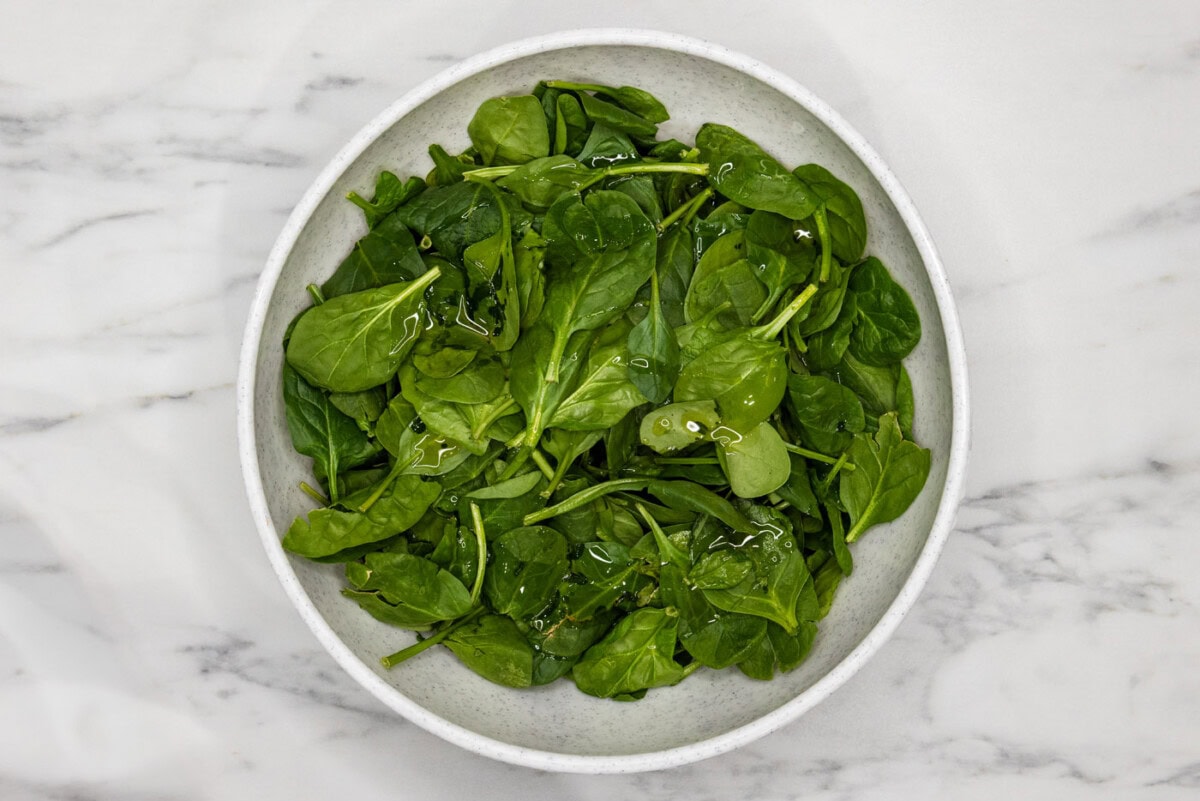 spinach in a bowl tossed with oil
