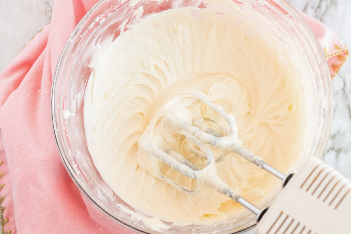 Frosting in a bowl with a hand mixer resting on the side