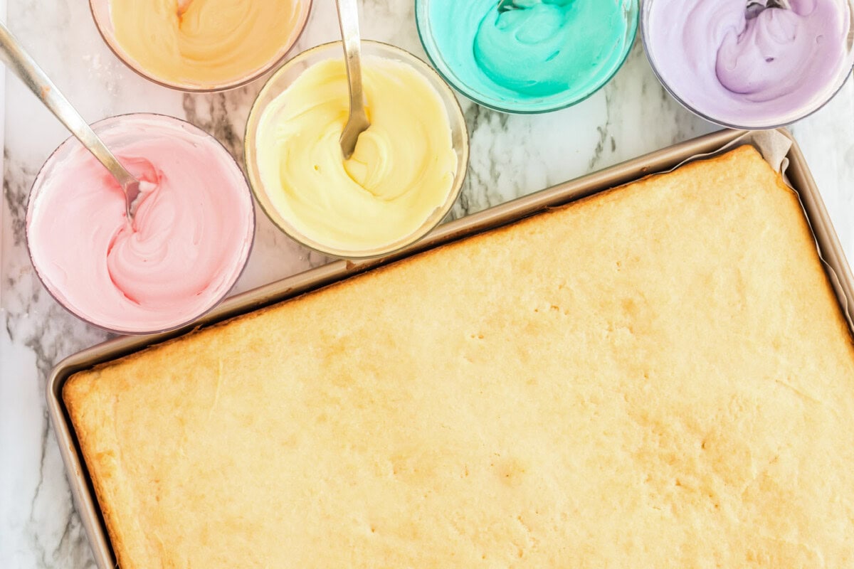 Jelly roll pan of sugar cookies and bowls of colored frosting