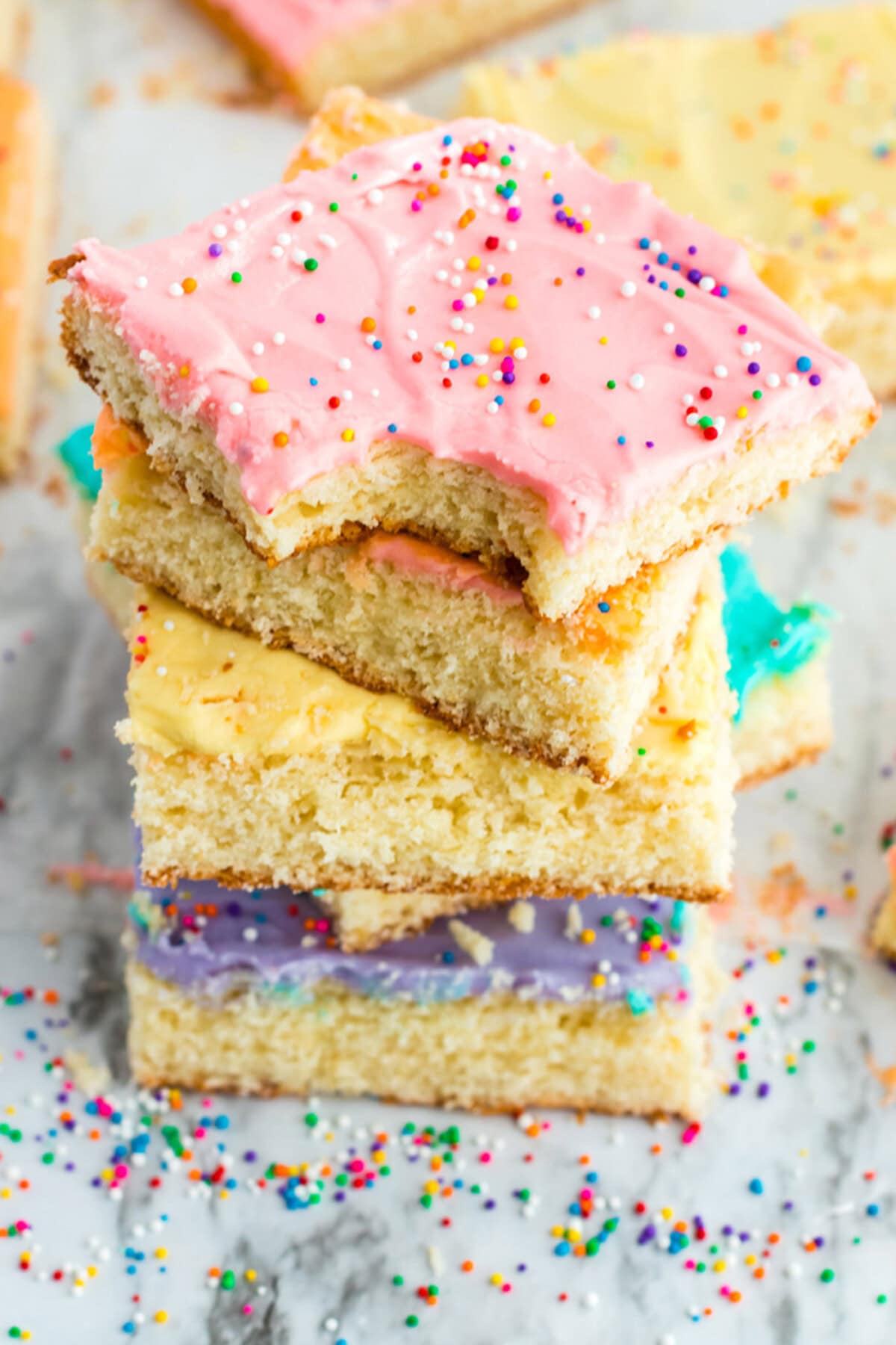 Stack of Frosted Sugar Cookie Bars with a bite taken out of the top one