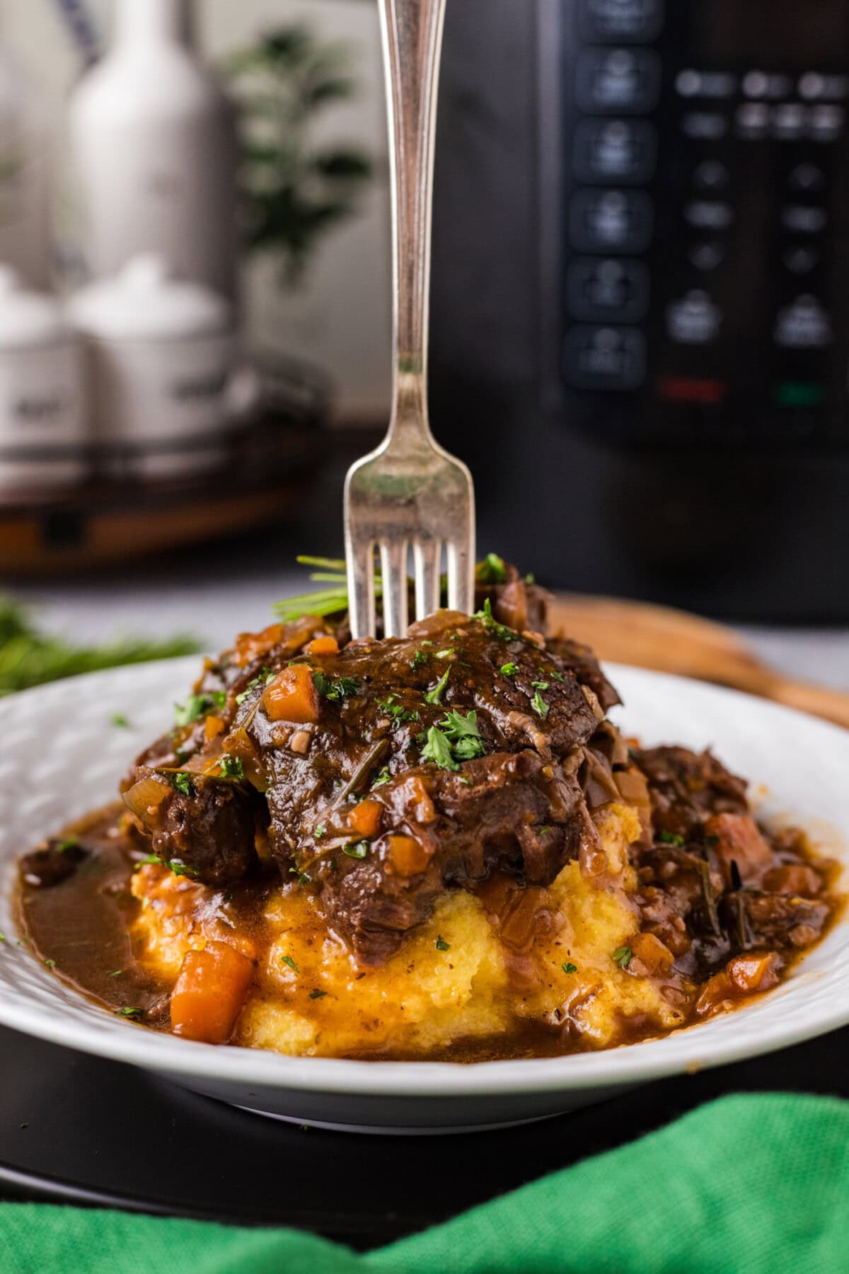 Fork stuck into Instant Pot Beef Shanks plated over mashed potatoes