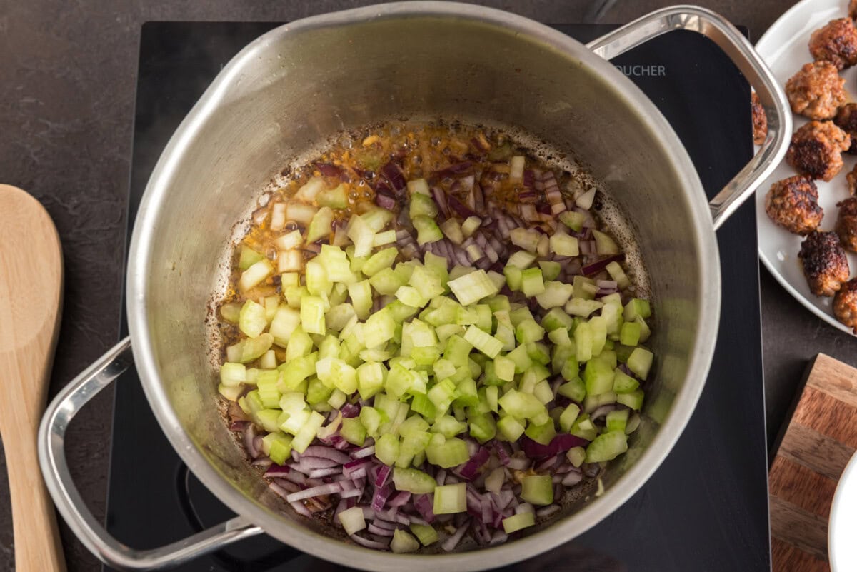 onion and celery added to soup pot with sausage and orzo
