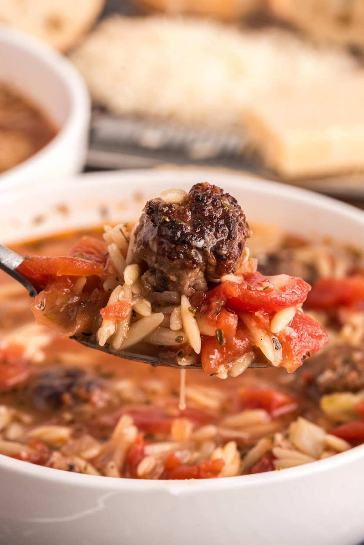 Close up photo of a spoonful of Italian Sausage Tomato Orzo Soup