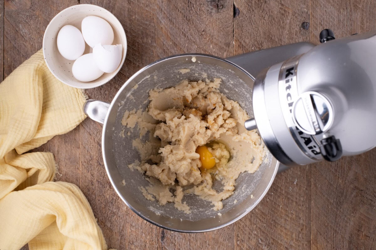 adding eggs to butter and sugar mixture in a mixer