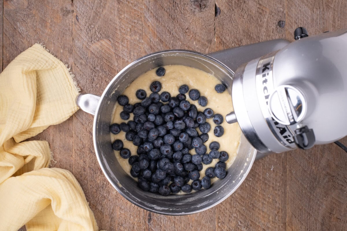 blueberries added to lemon cake batter in a mixer bowl