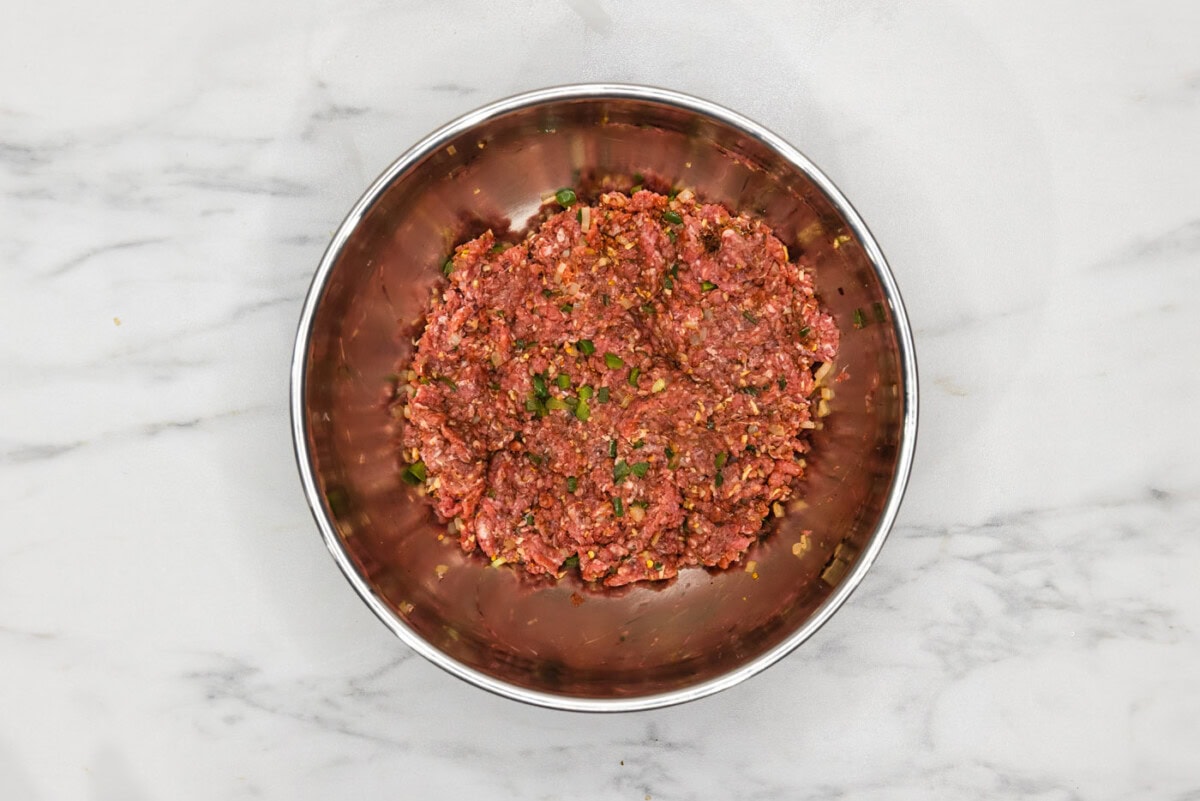 ground beef with diced jalapenos and onions in a bowl