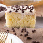 Close up photo of a slice of Cannoli Poke Cake on a spatula
