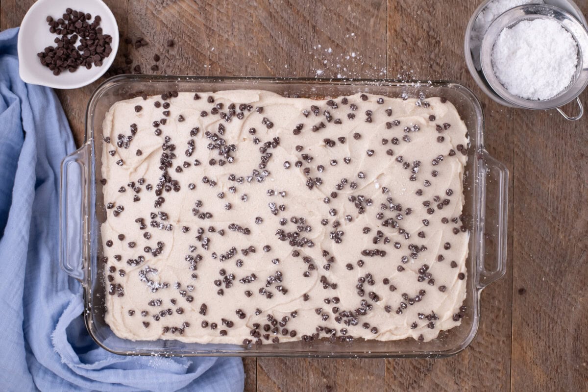 mini chocolate chips and powdered sugar over cannoli poke cake