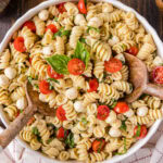 Close up photo of Caprese Pasta Salad in a bowl with two spoons