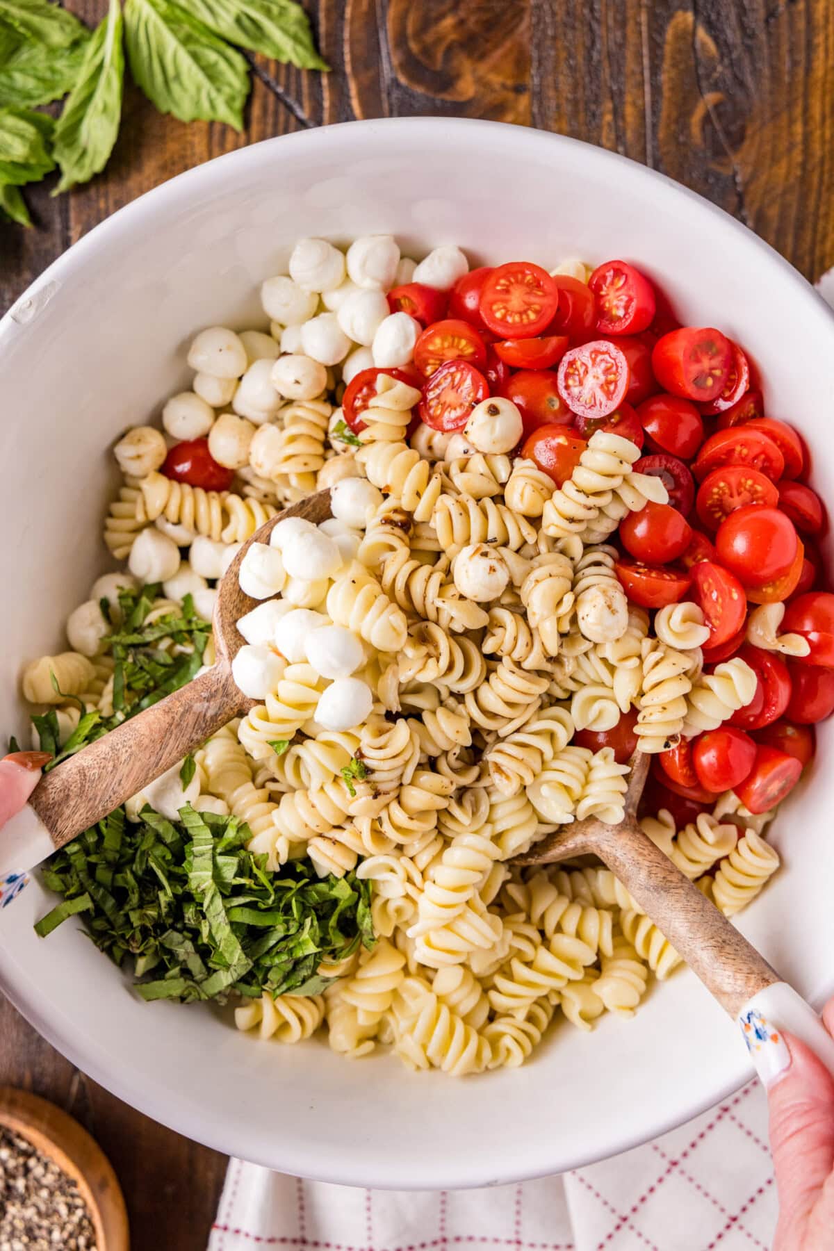 Caprese Pasta Salad being mixed in a serving bowl