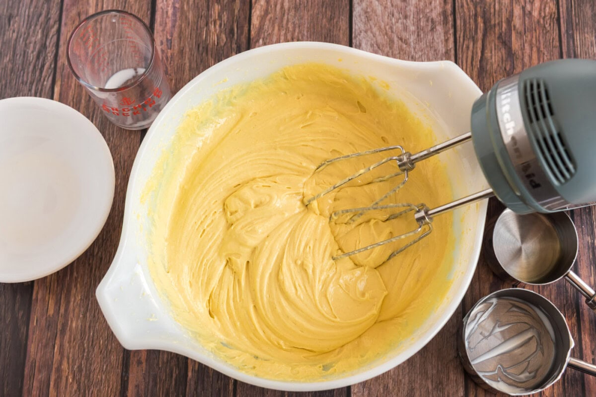 lemon cake batter in a mixing bowl with whisk beaters