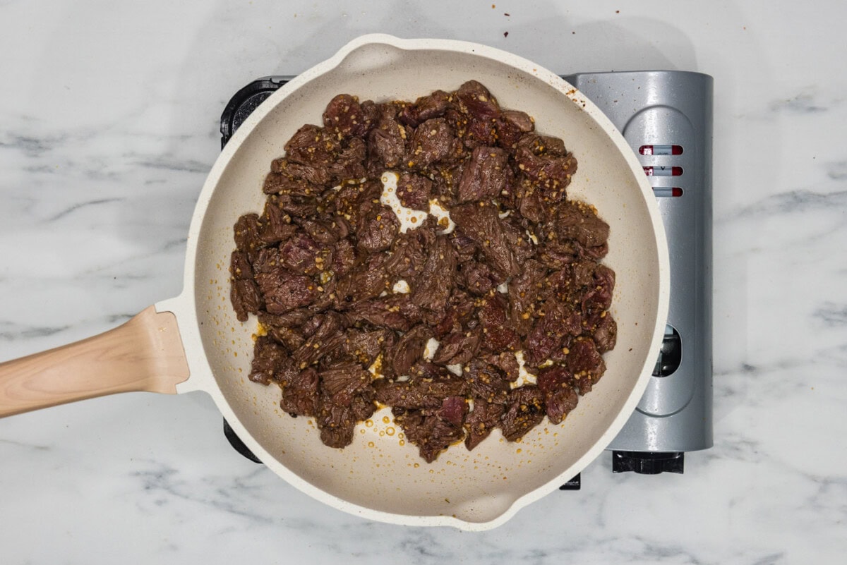 sliced steak and seasonings in a skillet