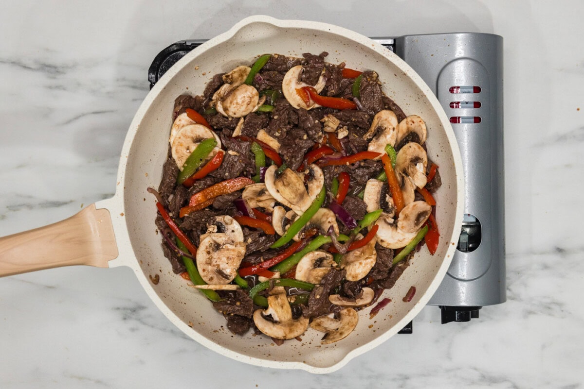mushrooms, peppers, and onions added to skillet with sliced beef