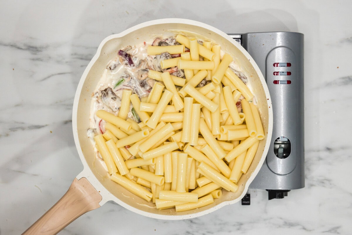 pasta added to skillet with meat, veggies, and cheese sauce