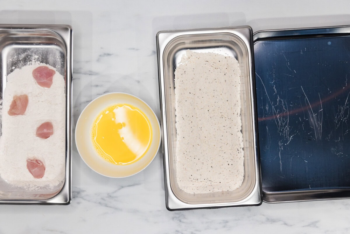 chicken in a breading tray with flour