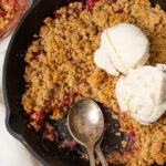 Close up photo of Rhubarb Crisp in a skillet topped with ice cream