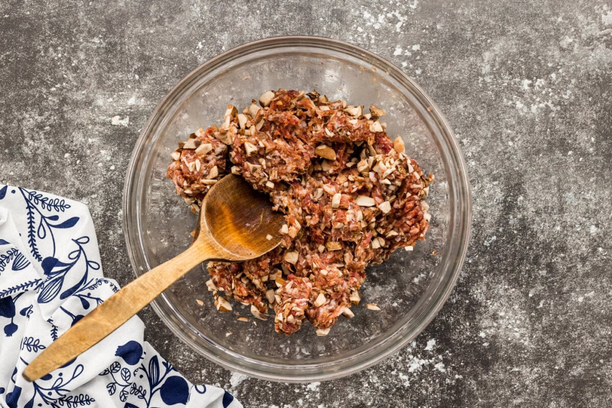 mixing sausage and mushrooms in a bowl