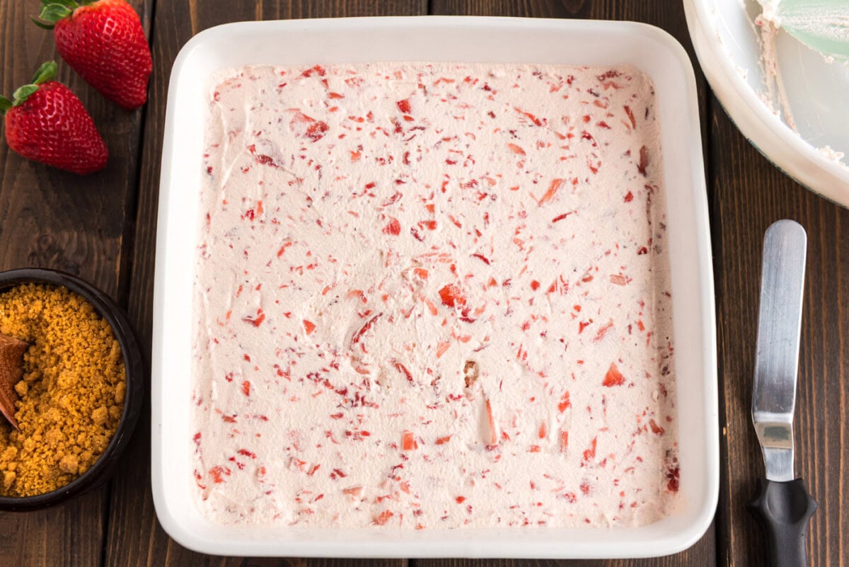 strawberry cool whip spread over cream cheese mixture in a pan