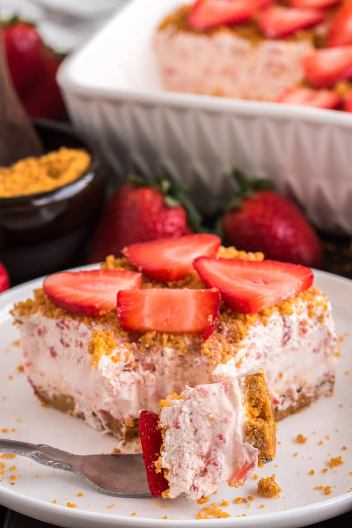 Strawberry Dream Dessert on a fork resting in front of a slice of Strawberry Dream Dessert