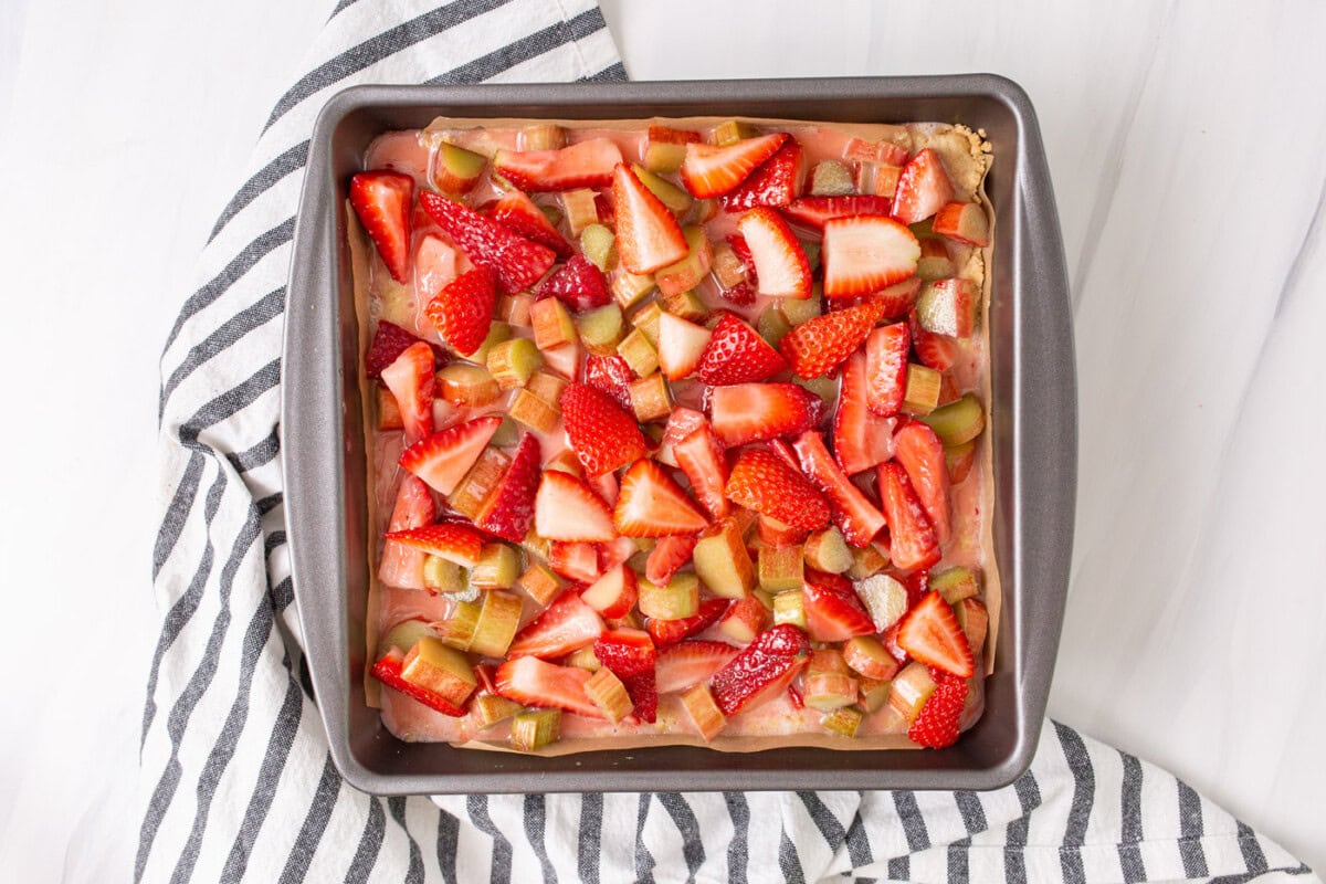 strawberries and rhubarb on top of crust in a pan