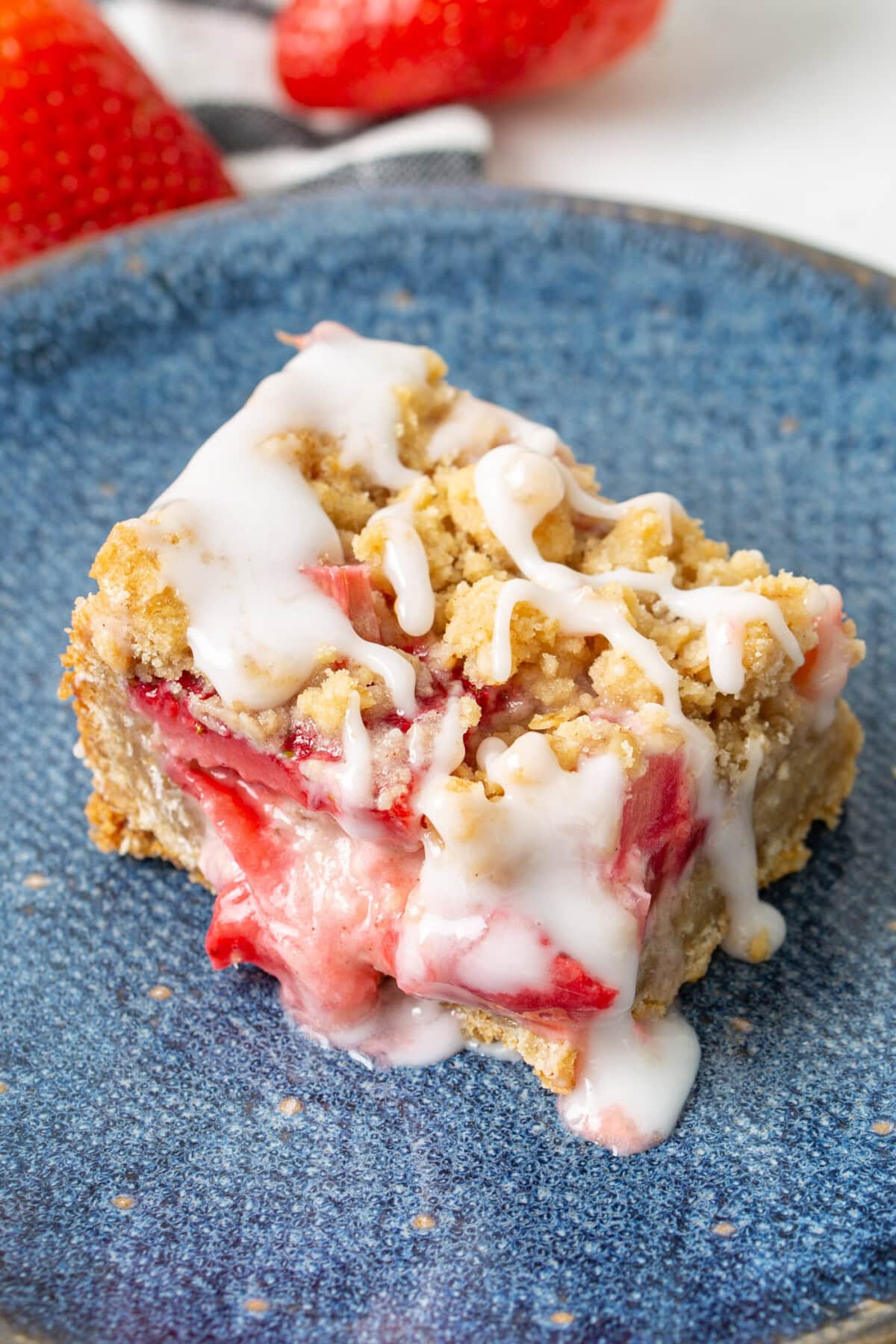 Close up photo of a Strawberry Rhubarb Crumble Bars on a blue plate