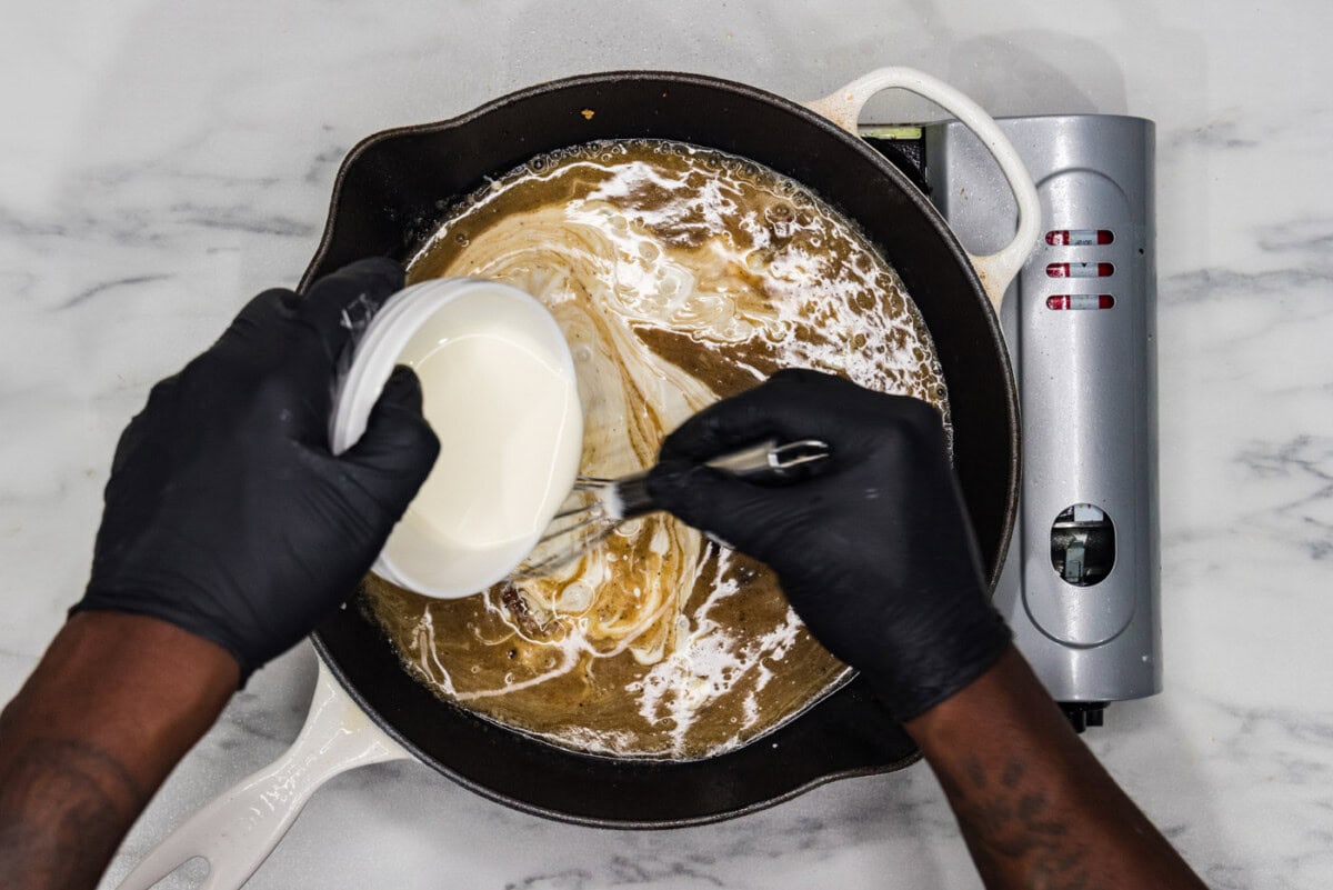 whisking heavy whipping cream into skillet with wine, lemon juice, and chicken base