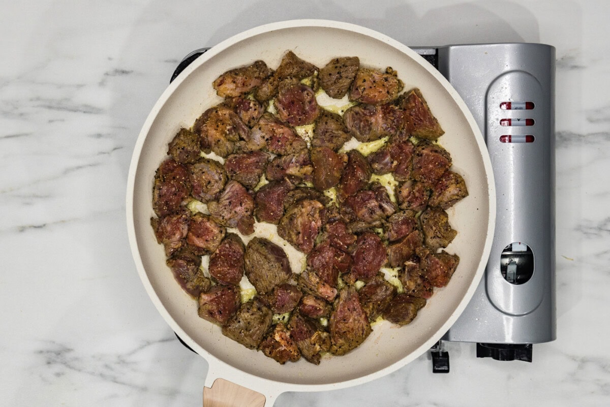 beef cubes cooking in a skillet