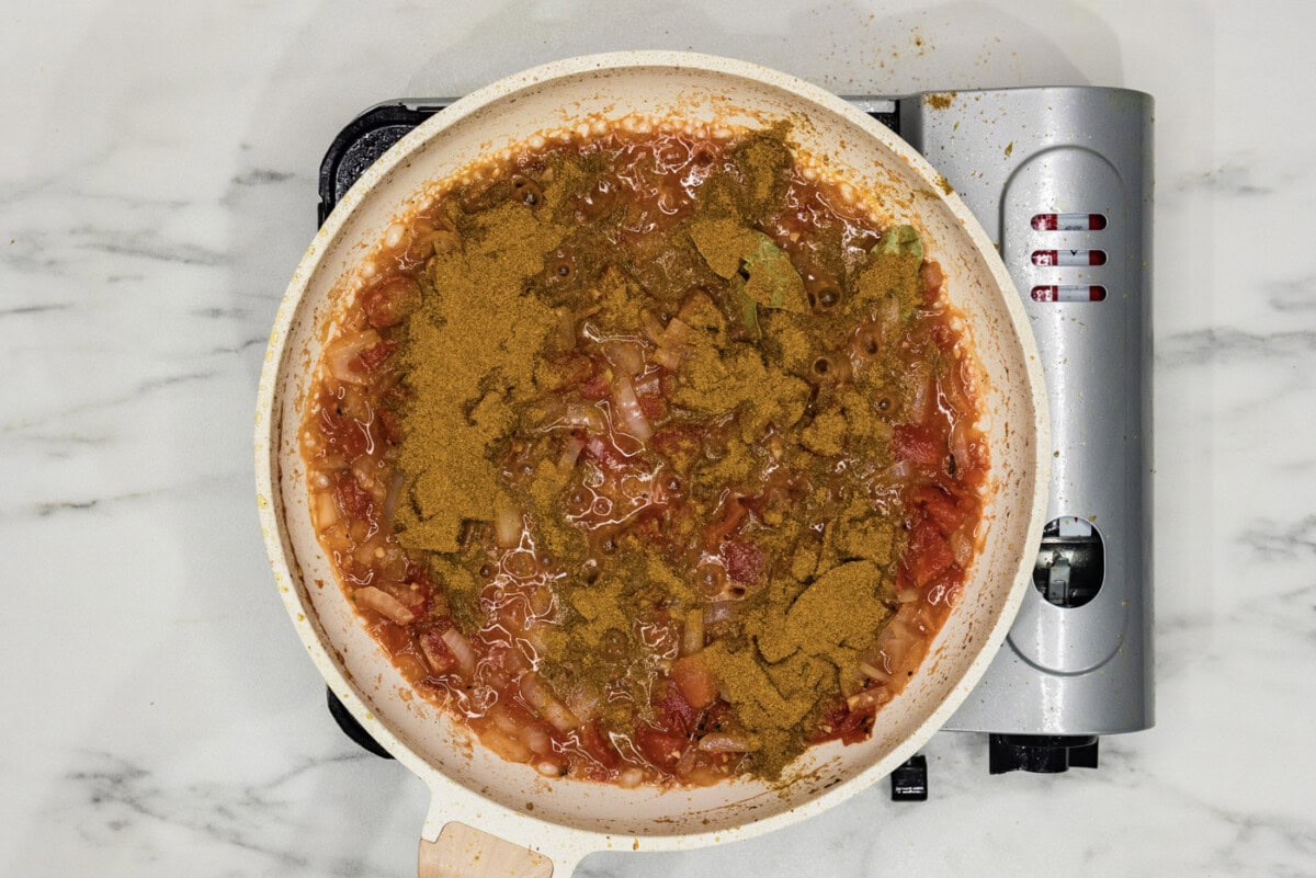 curry powder added to skillet with tomato based sauce