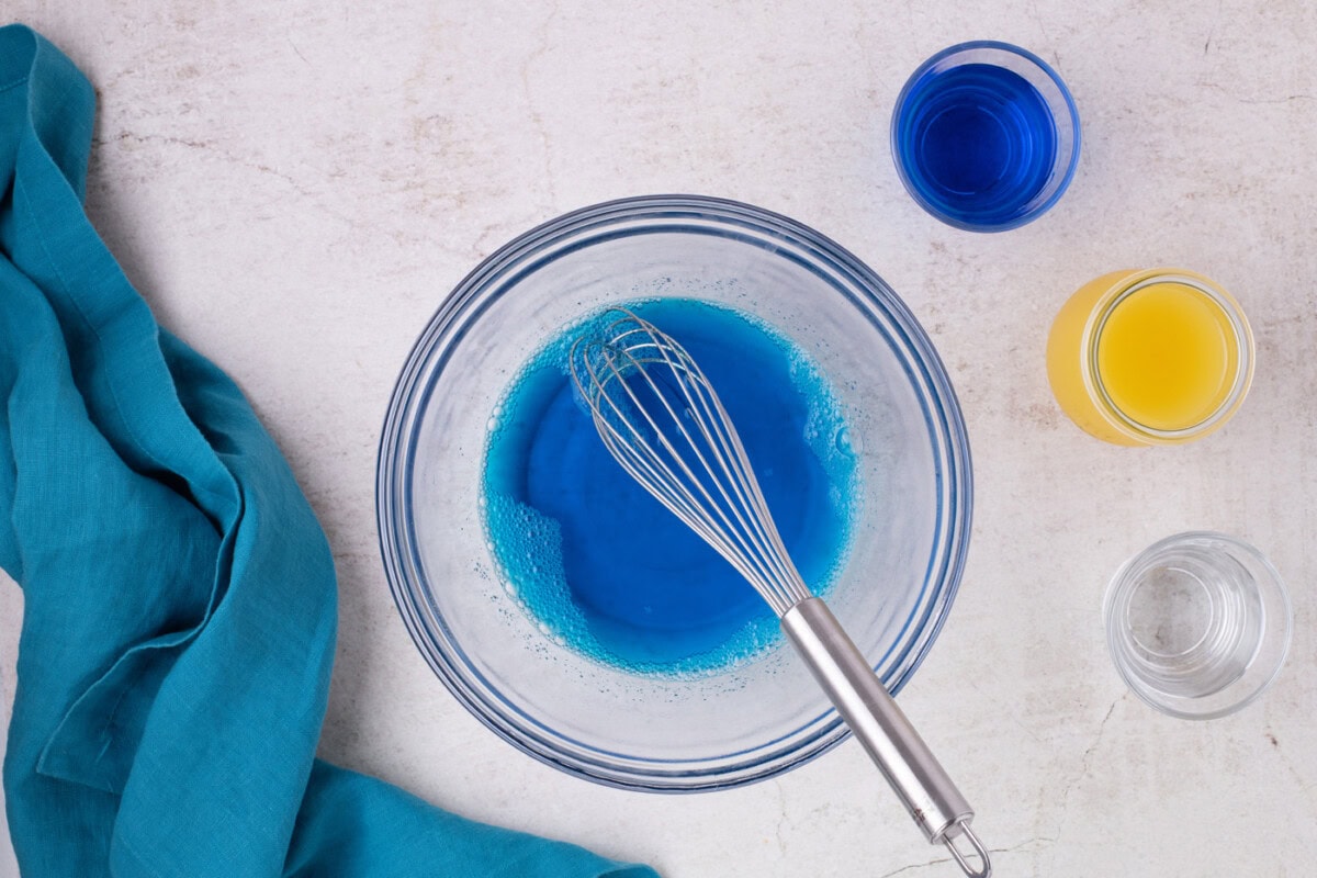 Whisk in a bowl with water and blue jello mixture
