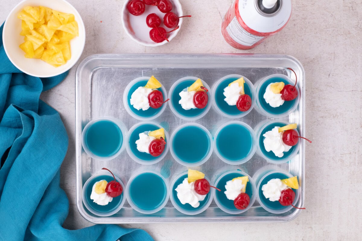blue hawaiian jello shots with whipped cream, cherries, and pineapple