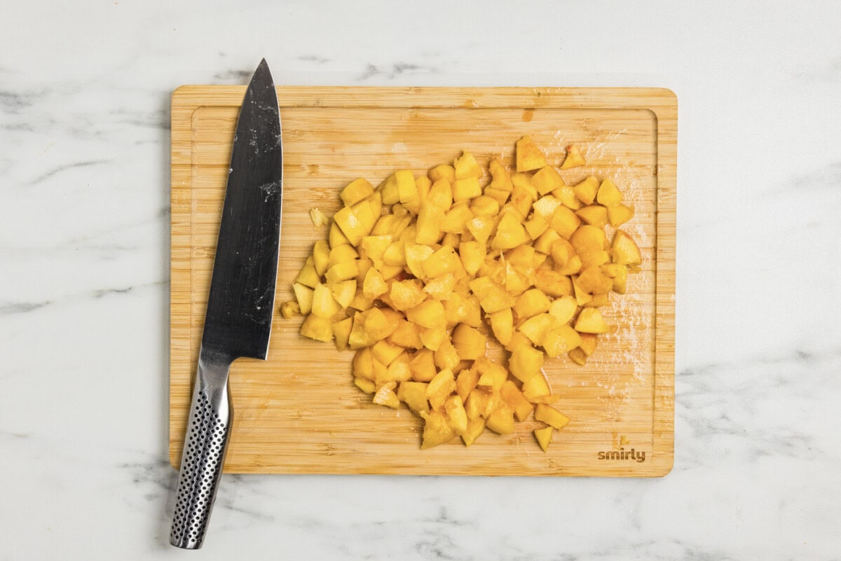 chopped peaches on a cutting board with a knife