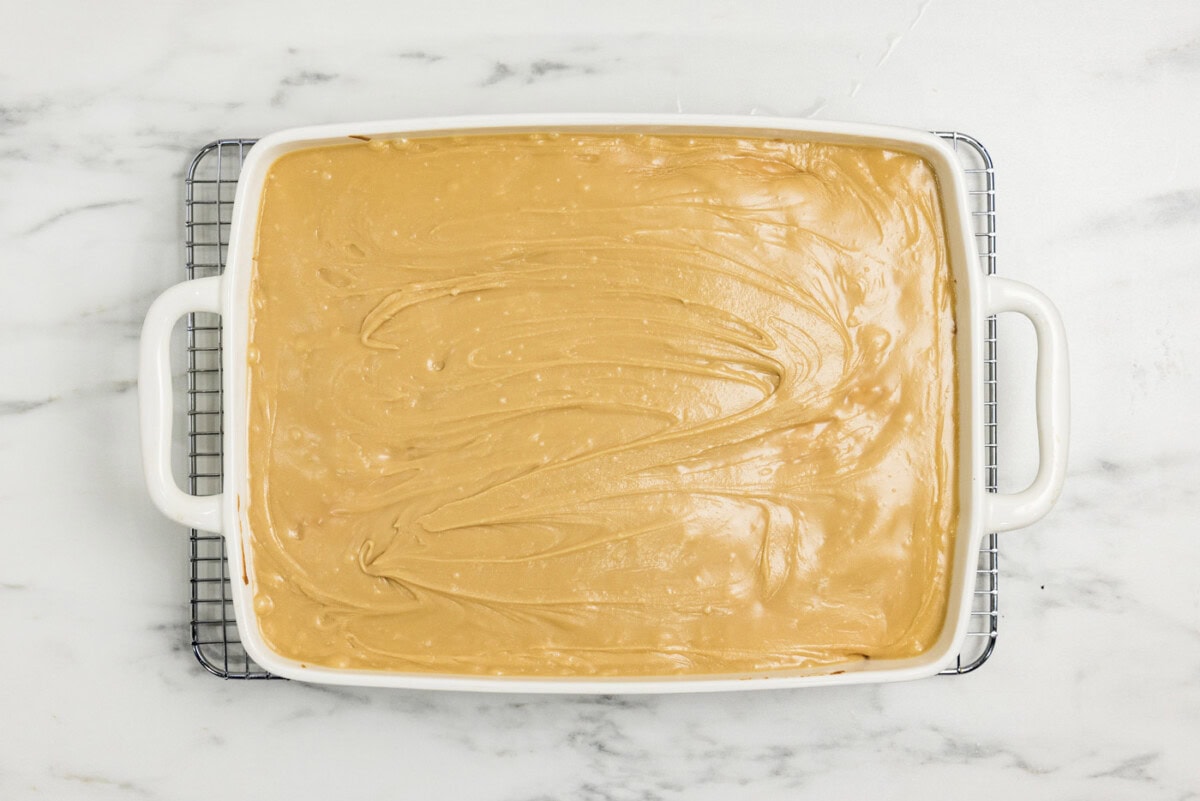 caramel icing spread over peach cake in a dish