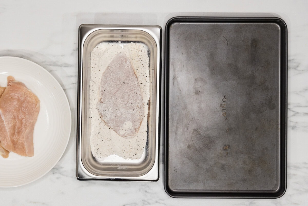 chicken cutlet in flour mixture breading tray