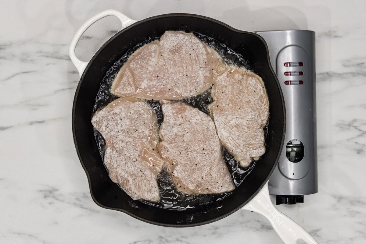 lightly coated chicken cutlets in a cast iron skillet