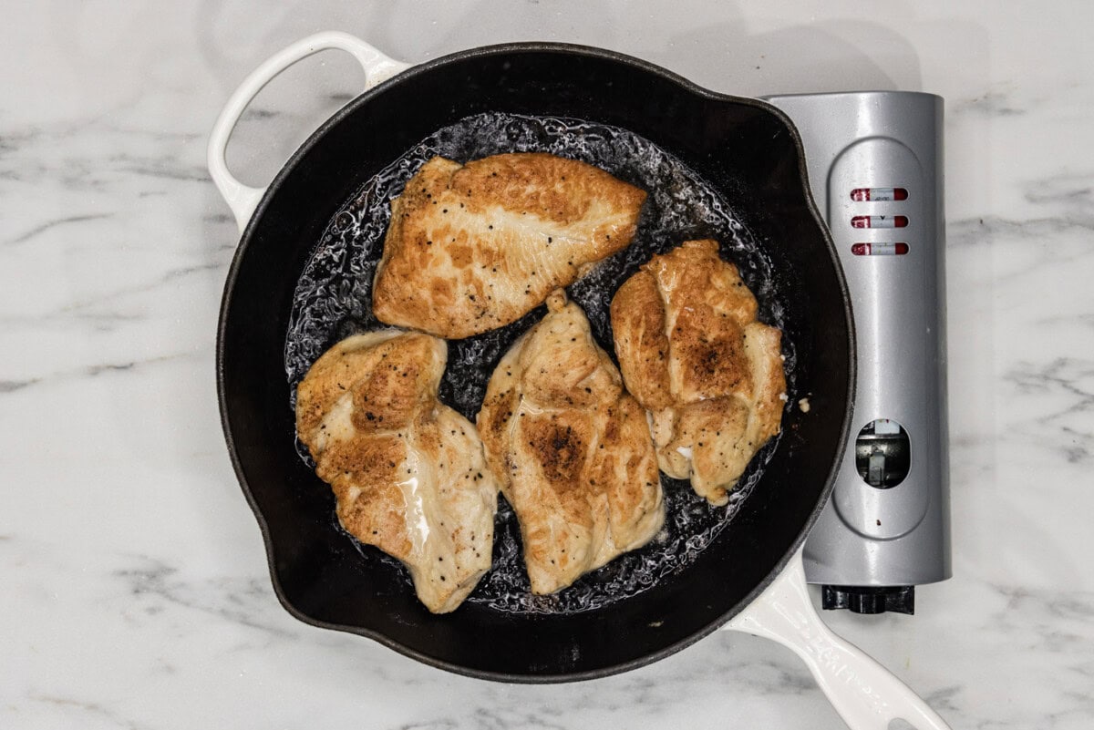 golden chicken cutlets in a cast iron skillet
