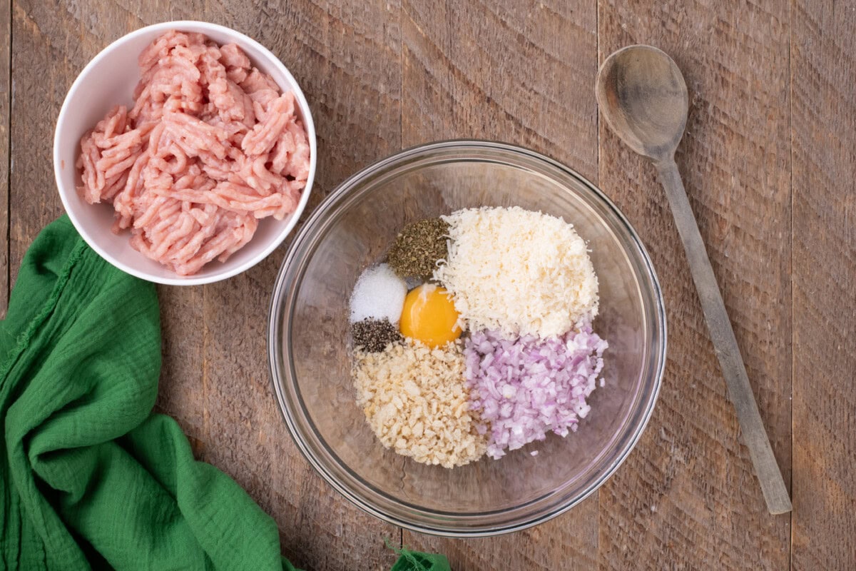ground chicken in a bowl next to meatball ingredients