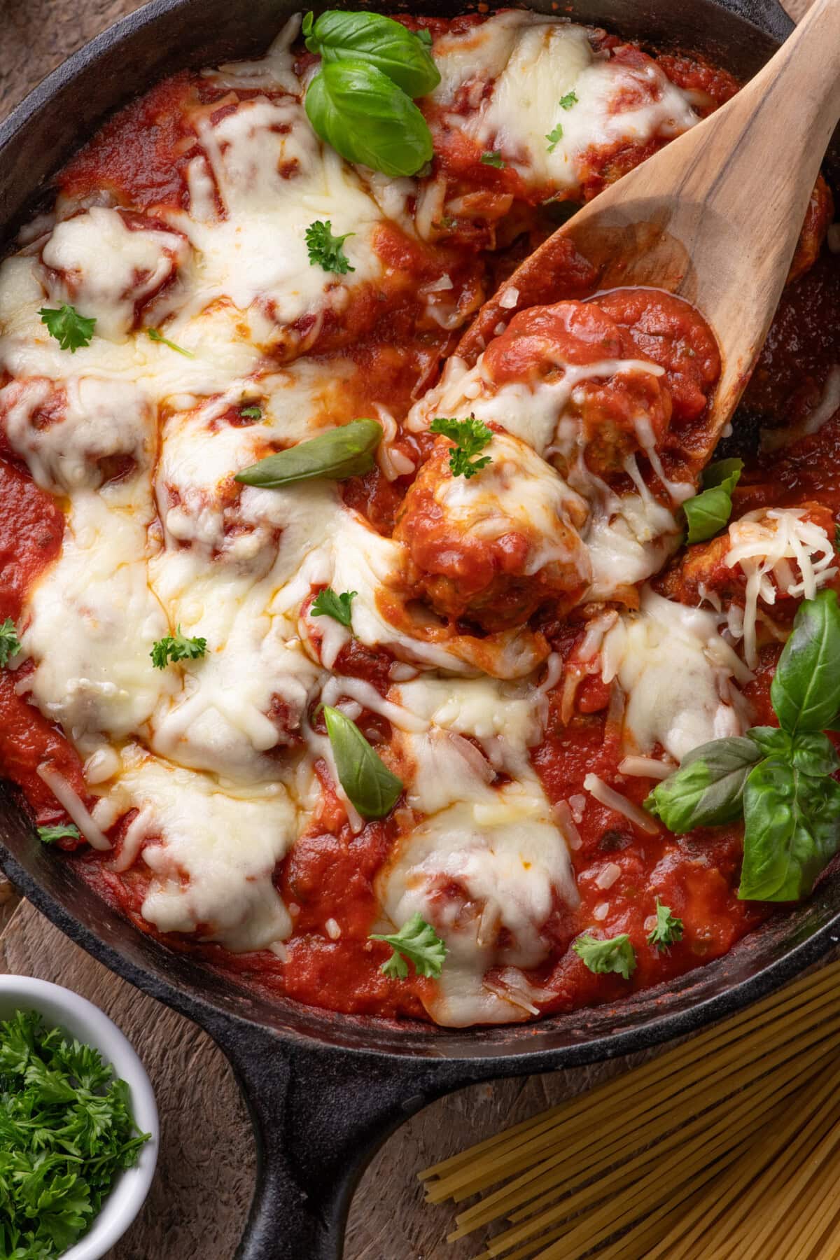 Close up photo of a spoon in a skillet of Chicken Parmesan Meatballs