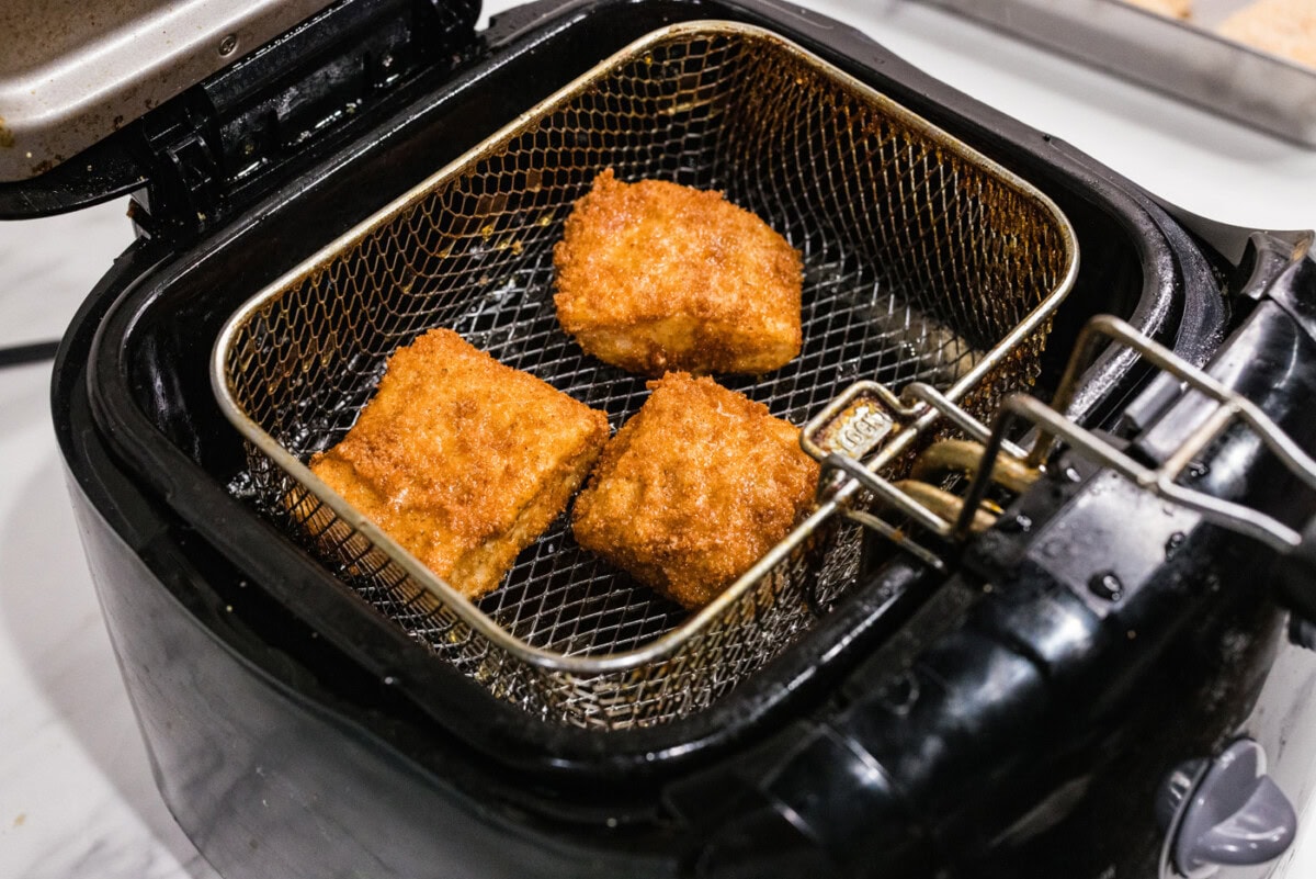 cooked cod patties in a deep fryer basket