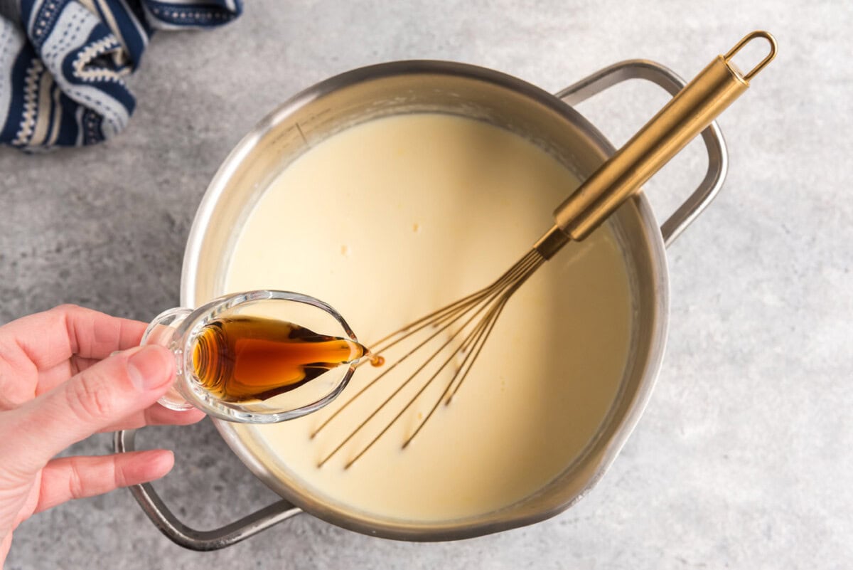 pouring vanilla into bowl of egg and milk mixture
