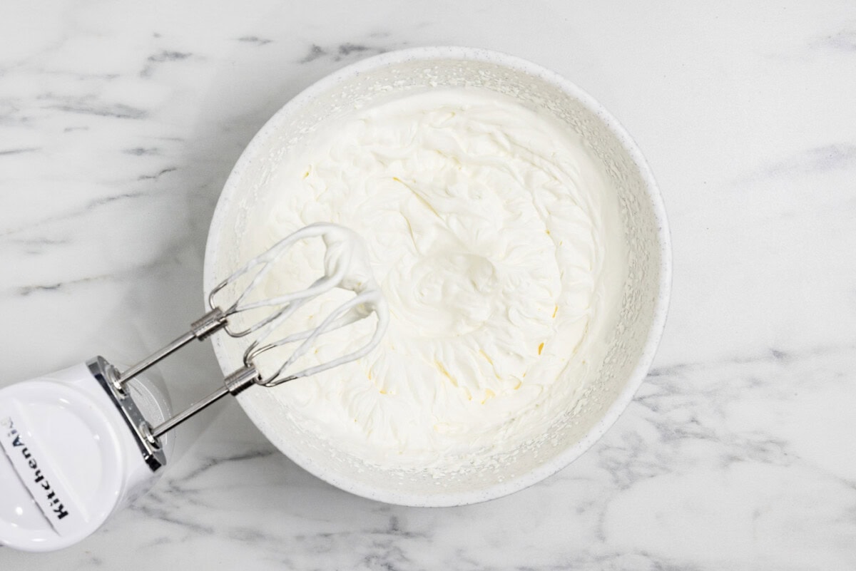 whipped cream in a bowl with electric mixer