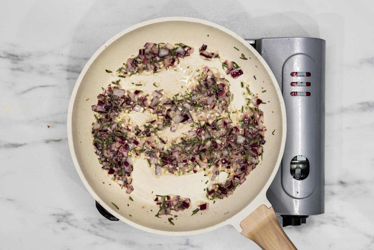 onion, garlic, and rosemary sauteeing in a skillet