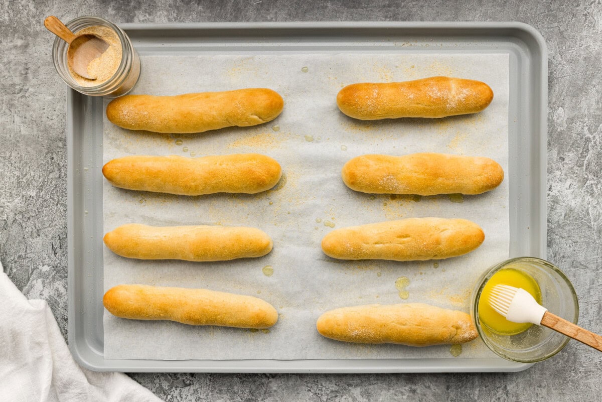 overhead of baked breadsticks on a baking sheet with butter and garlic salt