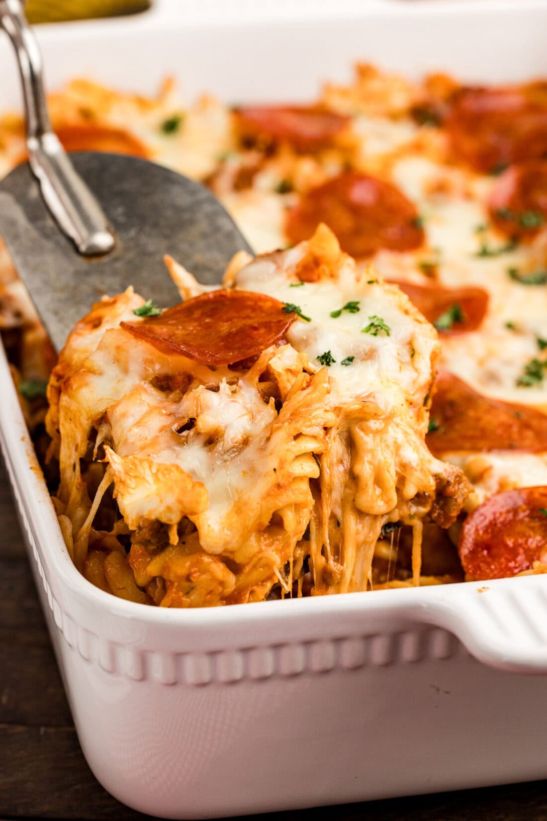 Scoop of Sausage & Pepperoni Pizza Casserole being lifted out of the casserole dish