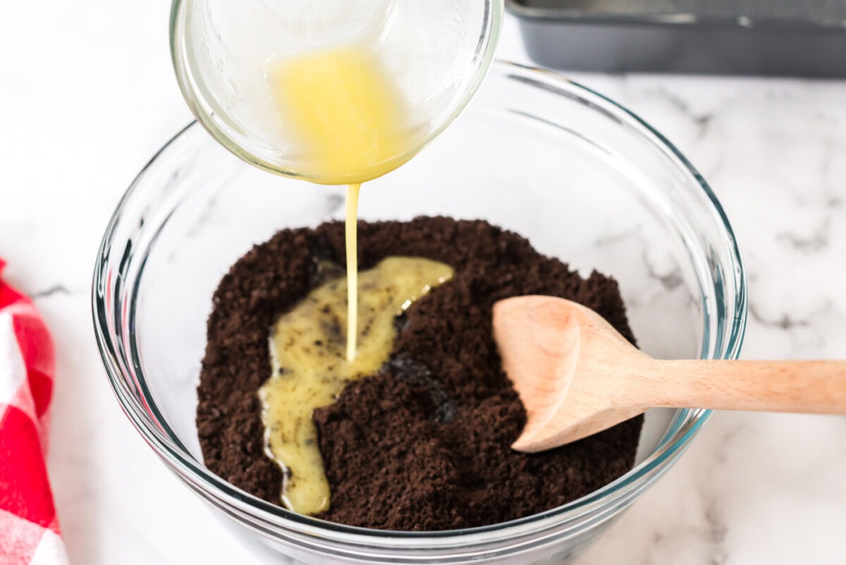 Butter being poured into oreo crumbs