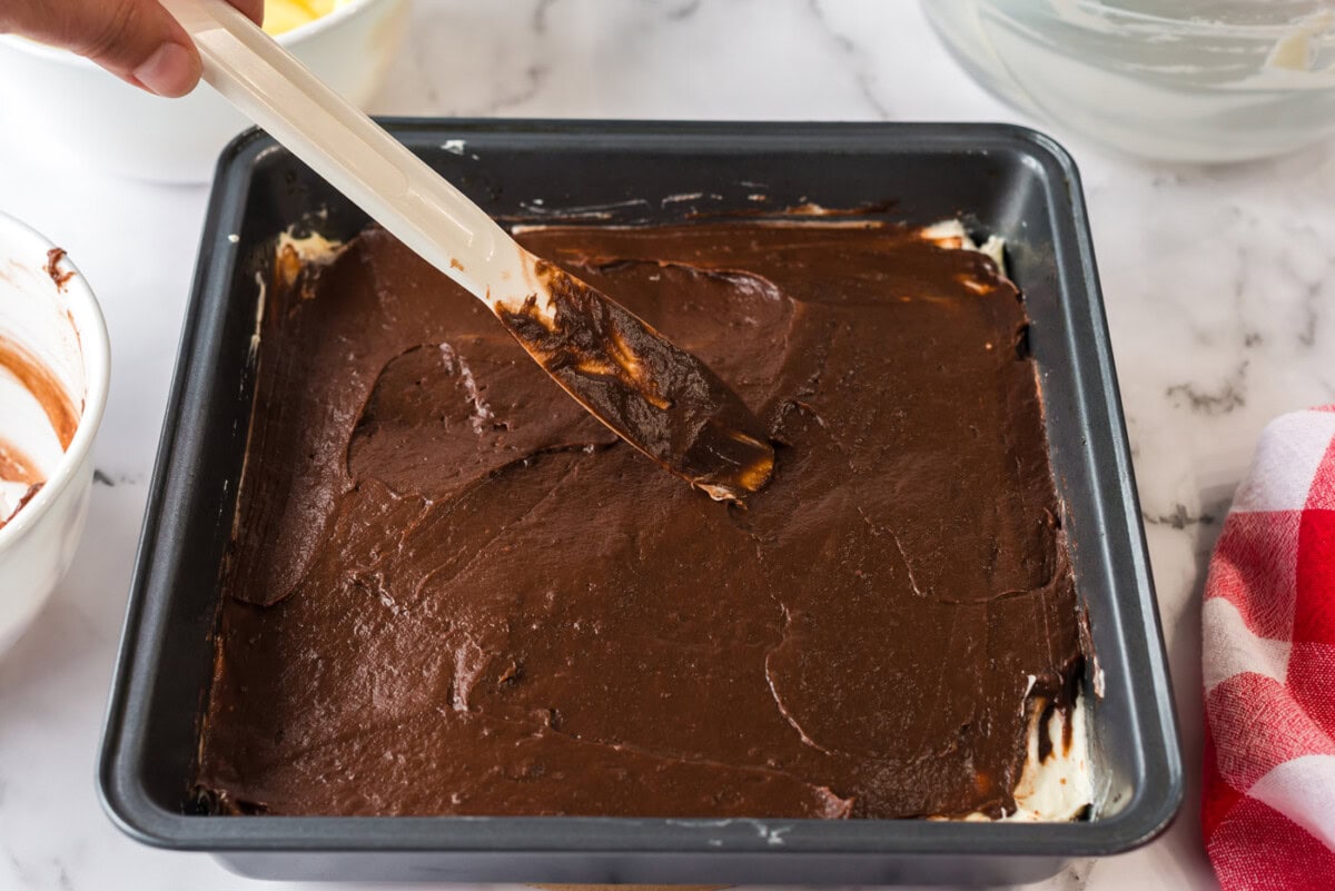 Chocolate pudding being spread over the cream cheese mixture