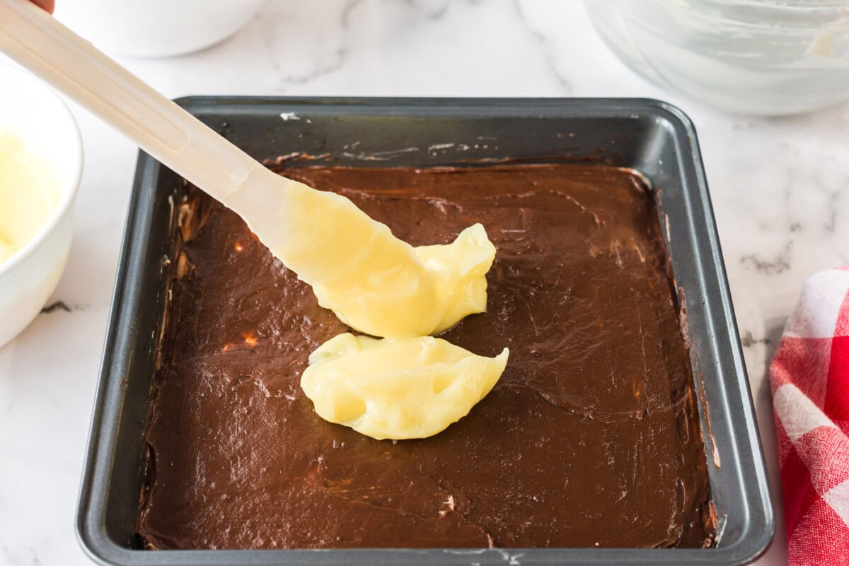 Vanilla pudding being dolloped on top of the chocolate pudding layer