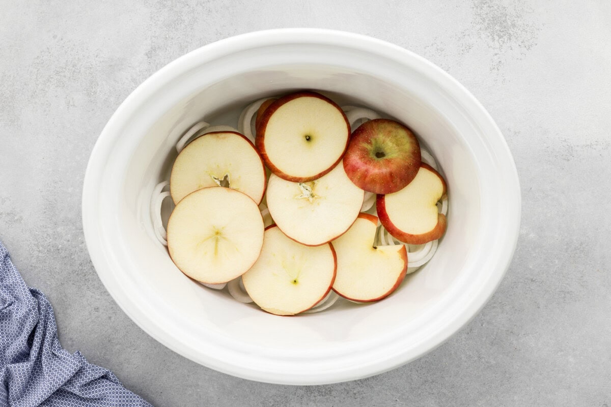 apple slices over onion slices in a crock