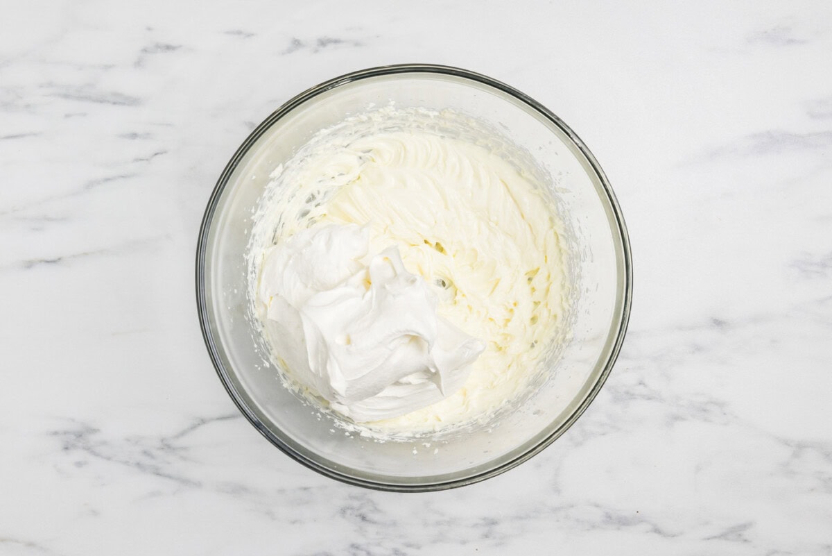 folding cool whip into cream cheese mixture in a bowl
