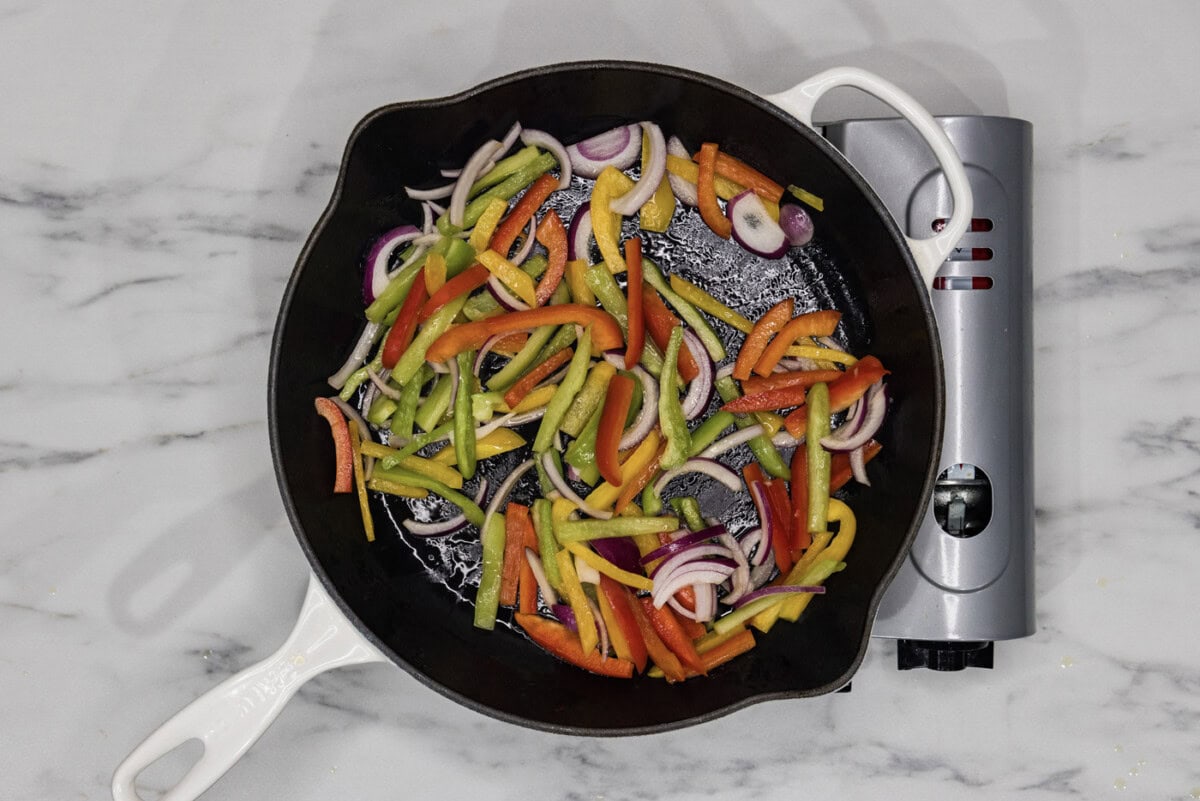 sauteeing bell peppers and onions in a skillet