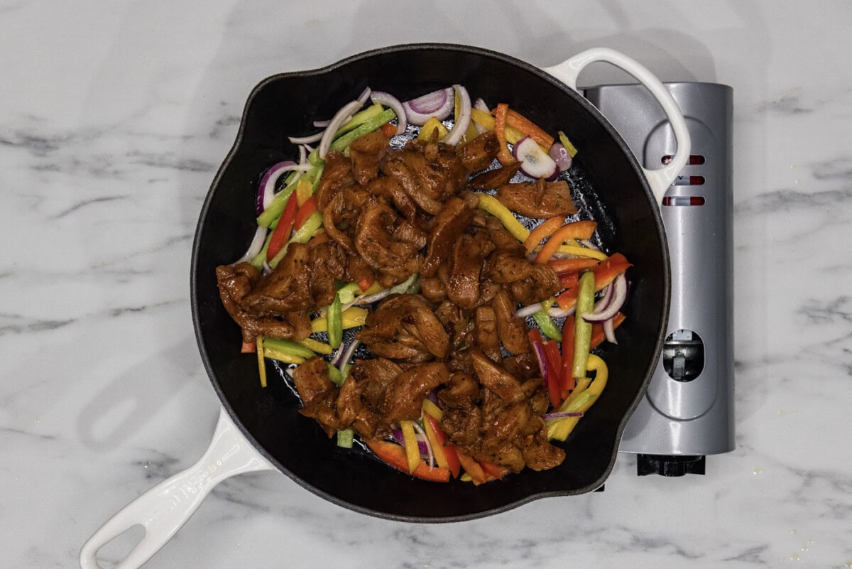 fajita chicken added to skillet with bell peppers and onions